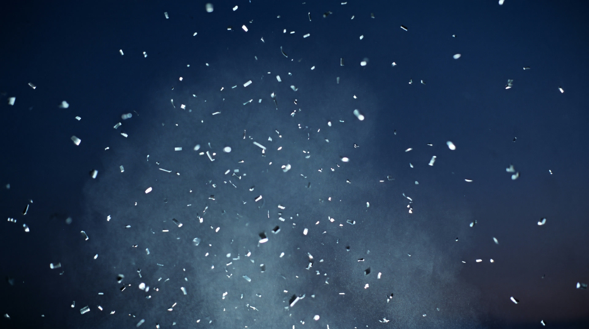 Silver fragments drifting in a deep indigo dusk